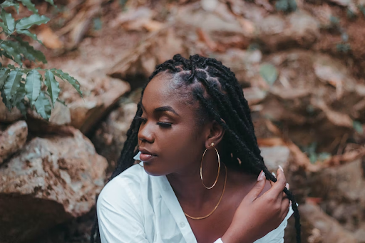 A model with faux locs in a natural setting.