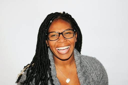 A smiling black woman with dreadlocks smiling.