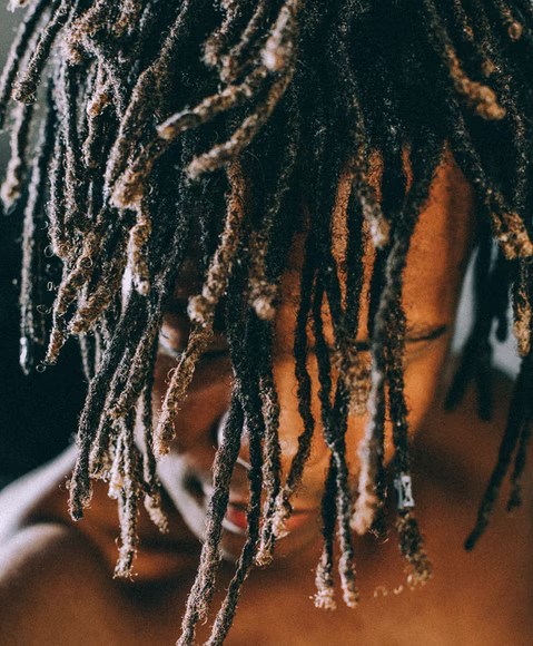A model draping his dreadlocks over his face.