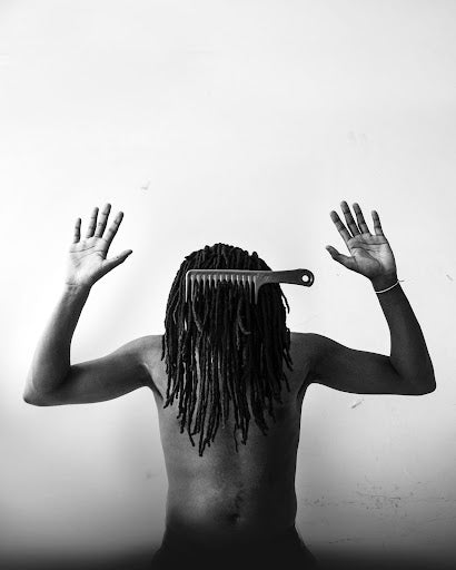 Man with hands up and his locs covering his face.