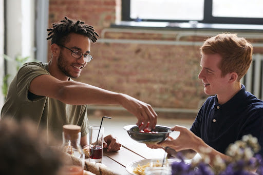 Two young men sitting together and one of them has starter locs.