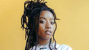 Woman with long dreadlocks with a yellow background.
