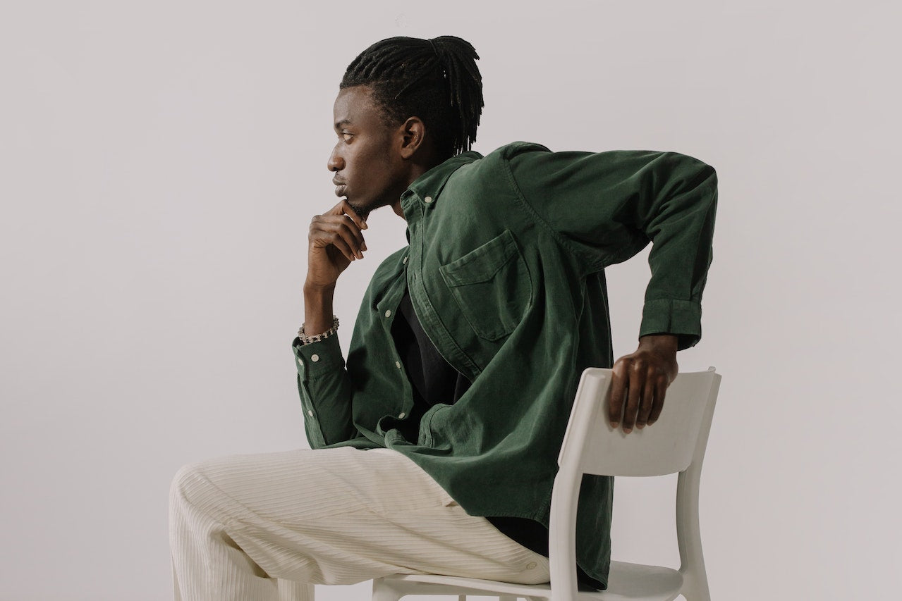 a man with dreadlocks posing on a chair