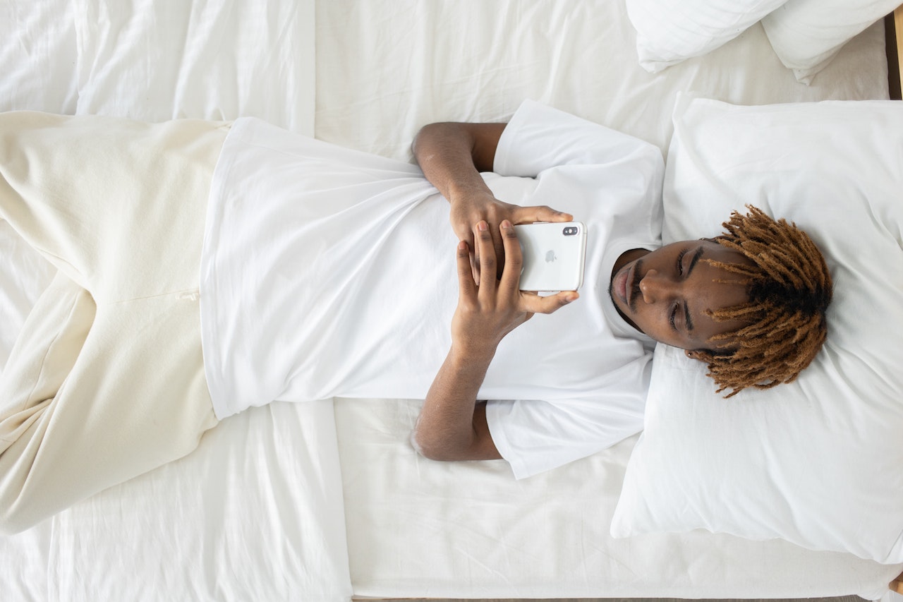 a man with small dreadlocks looking at his cellphone