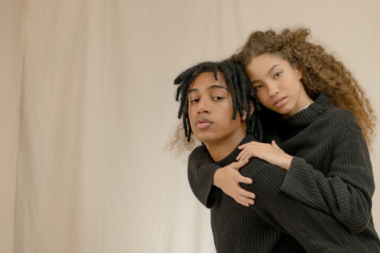 a woman with long hair hugging a man with dreadlocks