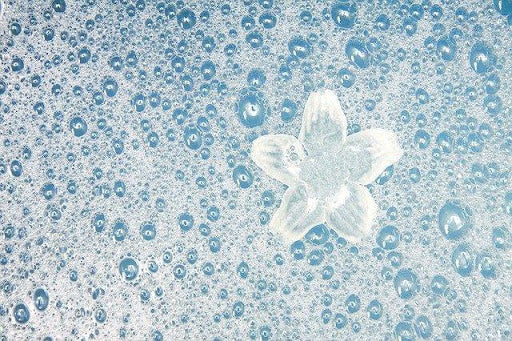 Blue water with suds and a white flower on top