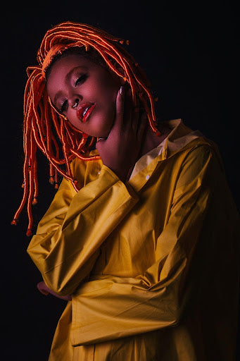 Person in yellow raincoat and copper-colored locs