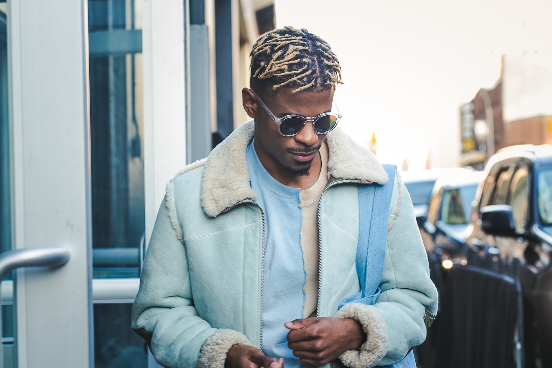 A man with bleached dreadlocks wearing a gray jacket