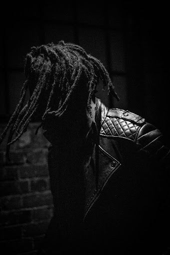 Side view of person with freeform locs wearing a leather jacket. 