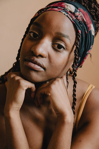 A black woman with braided faux dreadlocks looking somberly into the camera.