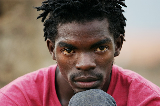 Close up of young black man with short dreadlocks. 
