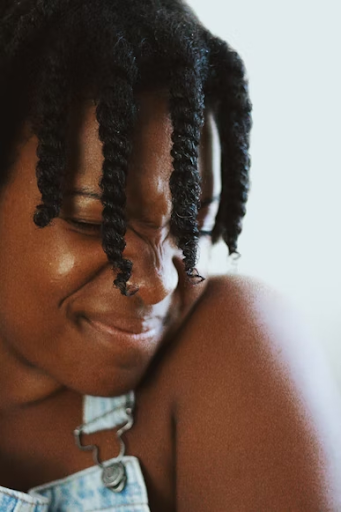 A smiling model with starter two-strand locs.