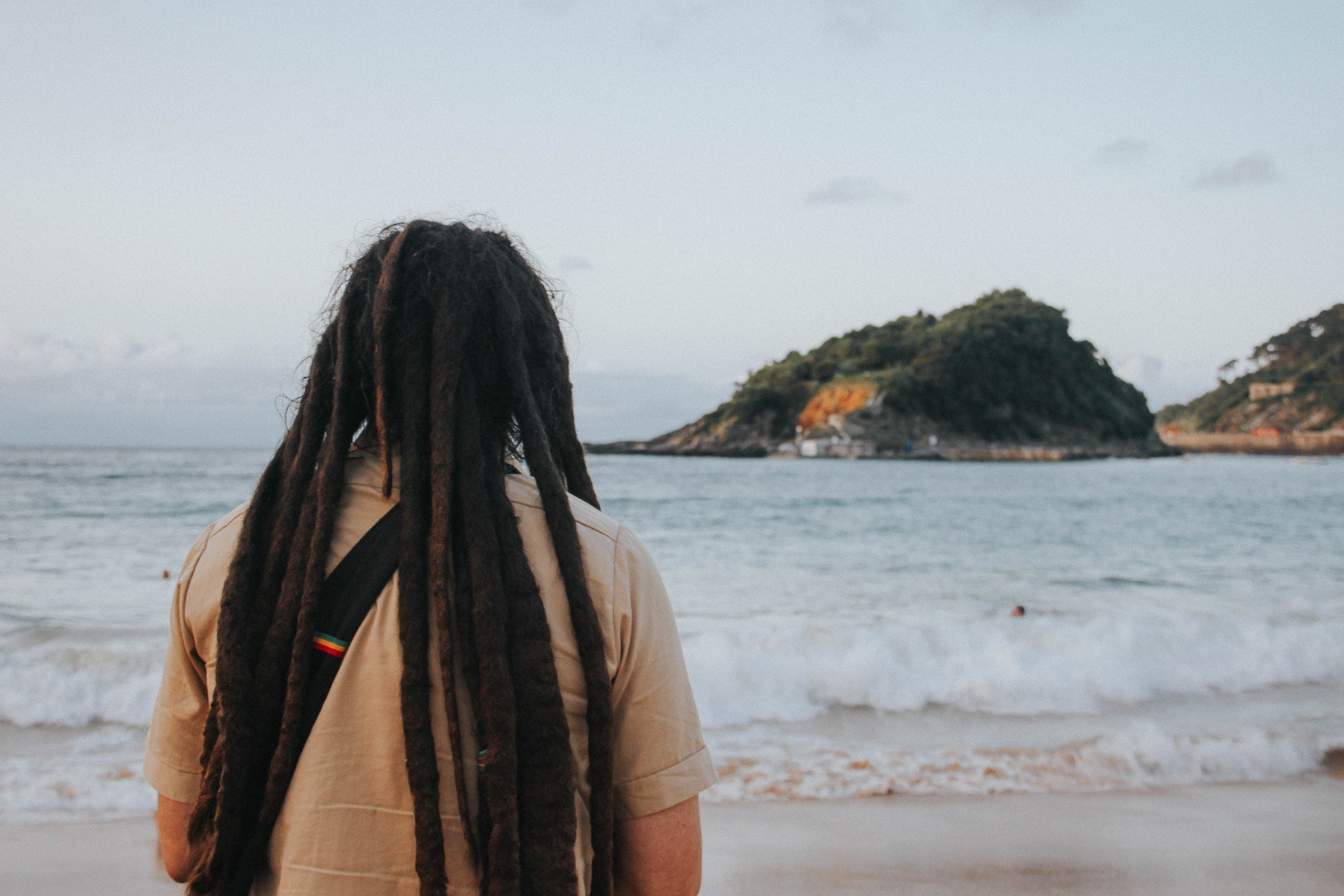 a man with dreadlocks looking at the beach