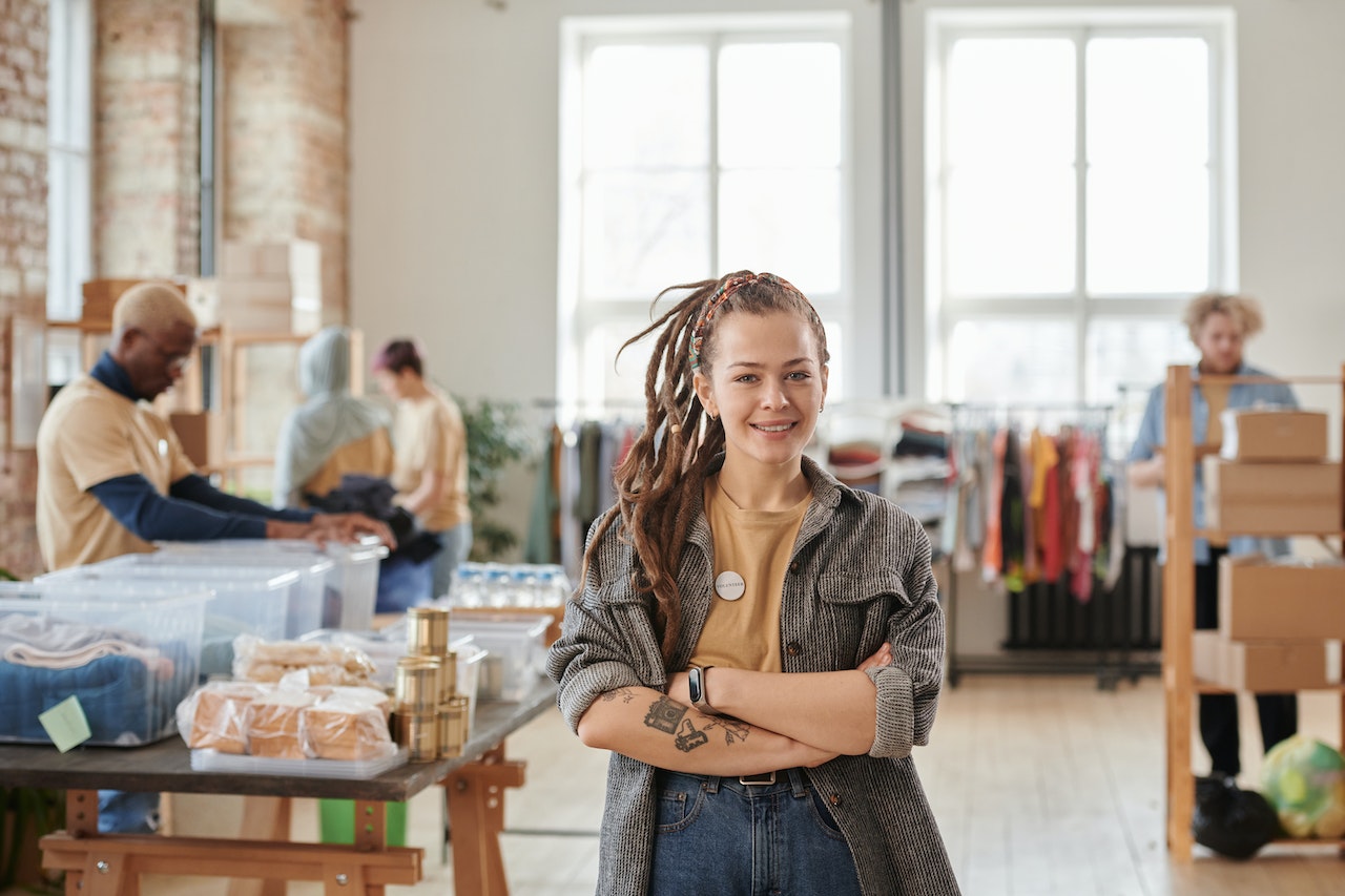 Woman with Dreadlocks Smiling and Standing with Arms Crossed in the Room