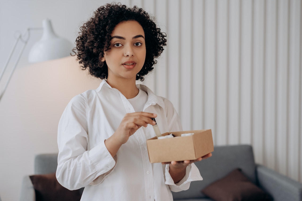 Woman in White Long Sleeve Shirt Holding A Box Of Essential Oils 