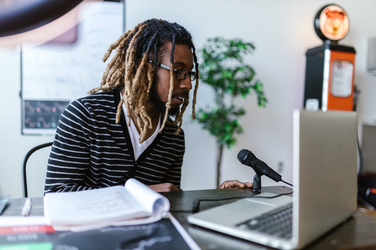 man with dreadlocks sitting in front of a computer