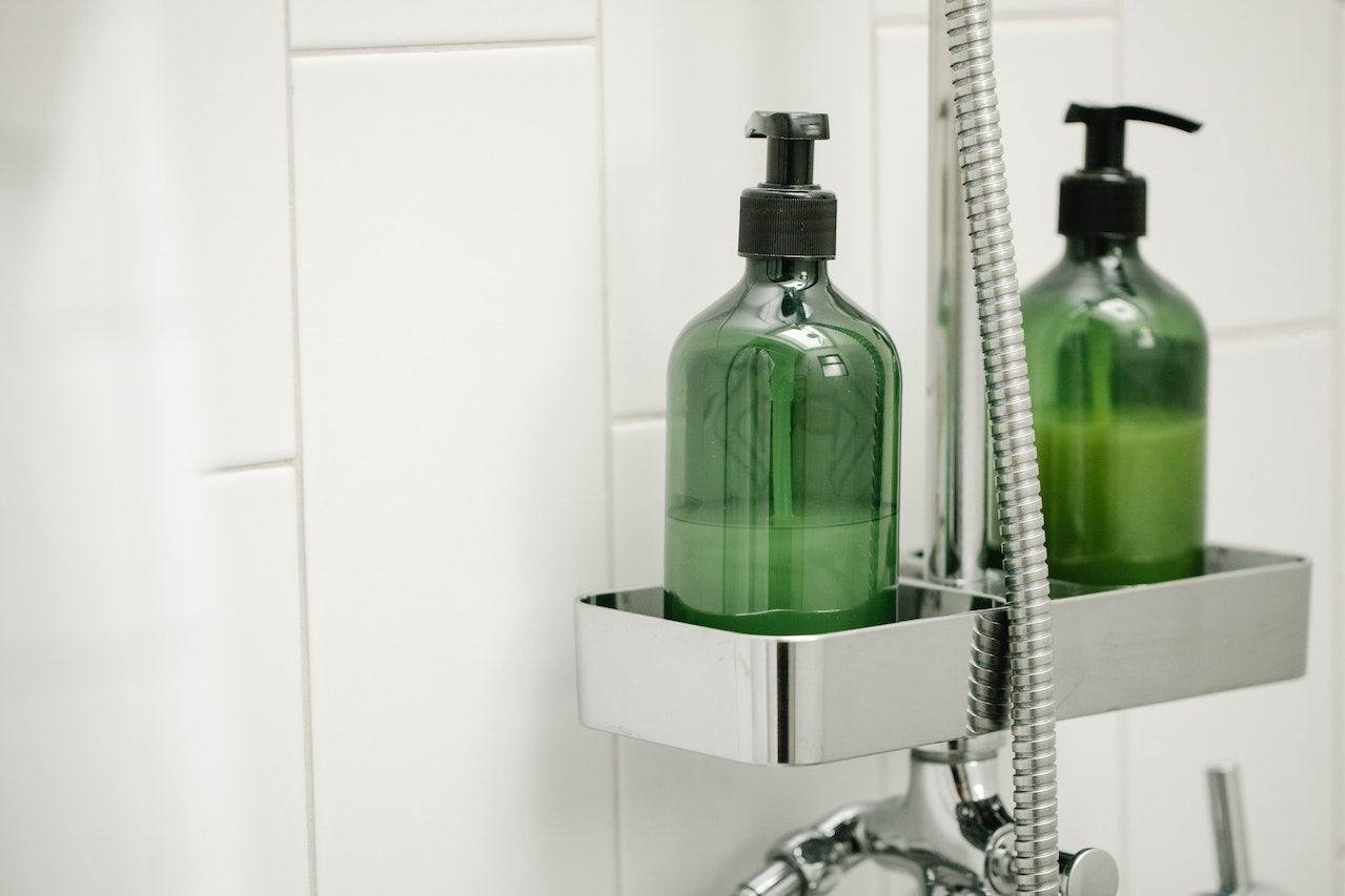 An image of green shampoo dispensers in the shower